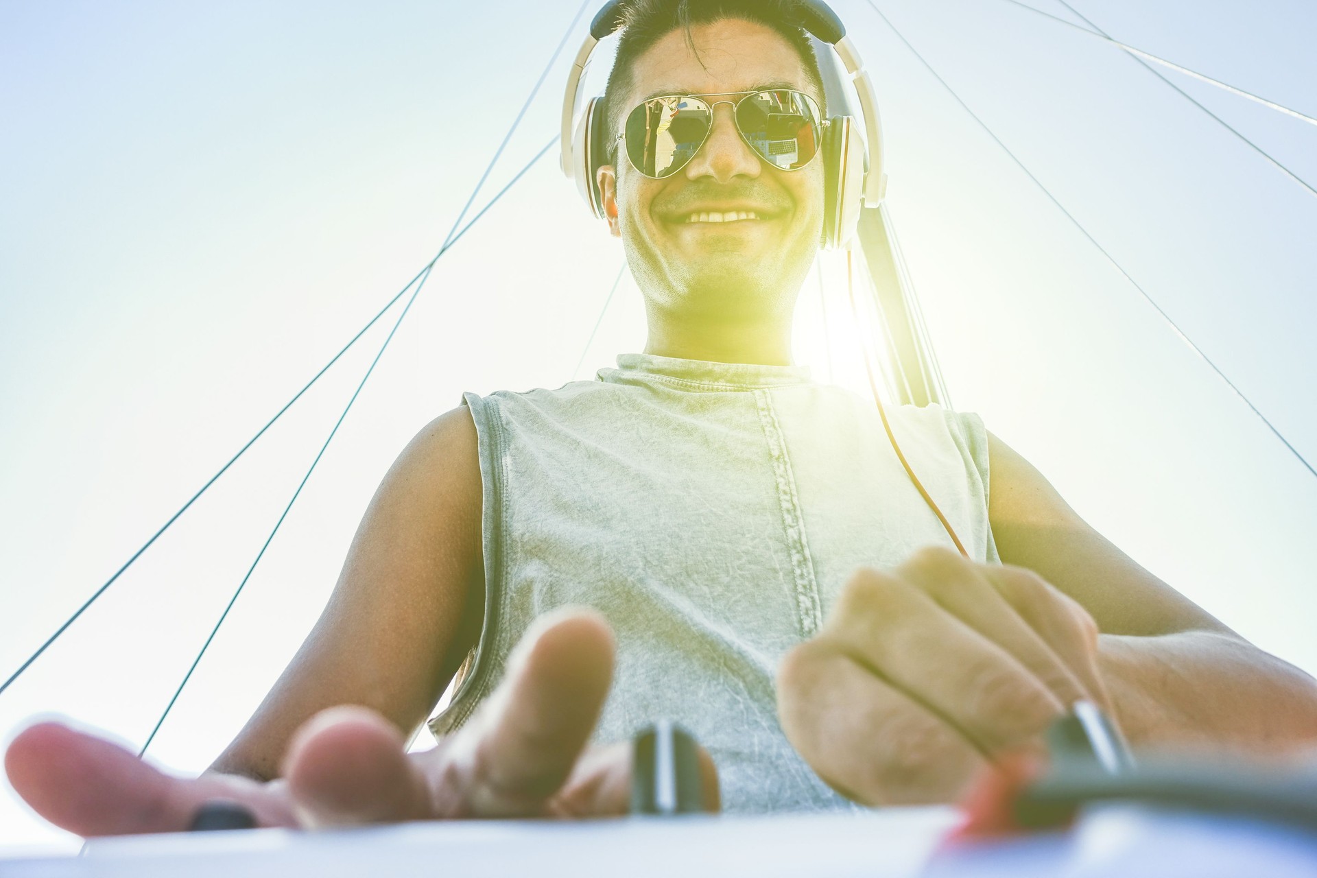 Cheerful dj mixing outdoor in boat party with back lighting in summer time - Portrait of young guy playing music for people entertainment at sunset - Fun and party concept - Warm vintage filter